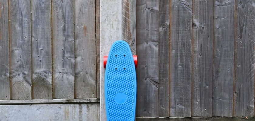 blue skateboard standing near the wall