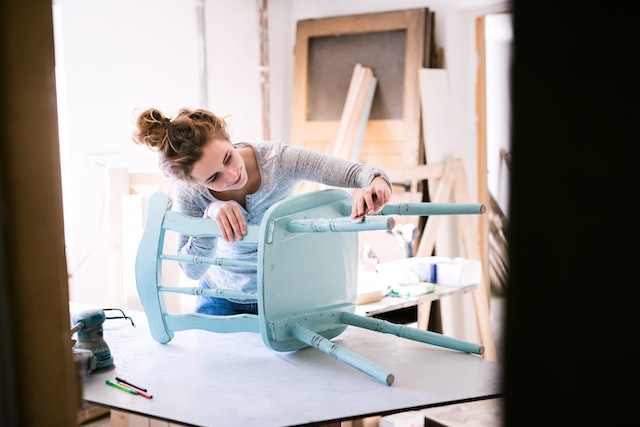 woman using sandpaper on a chair